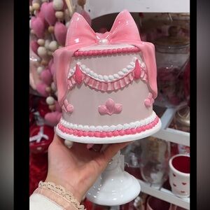 Valentine’s Day pink coquette bow cake decor on white stand / pedestal